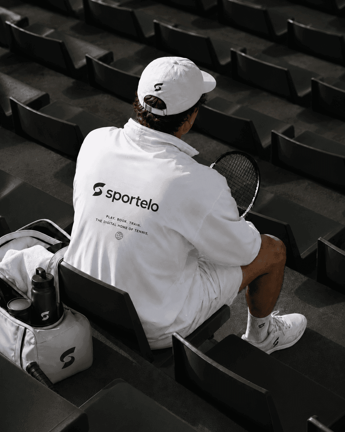 Tennis player in Sportelo branded shirt sitting in stadium stands